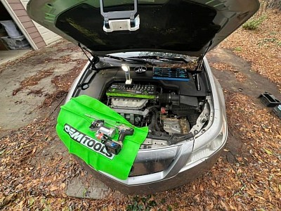 Un automóvil que exhibe una cubierta de capó verde, lo que resalta la atención de Mobile Auto Repair al detalle.