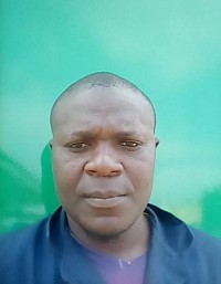 Un hombre vestido con una camisa azul se encuentra frente a un camión verde, representando a un ex cliente en un entorno relajado.